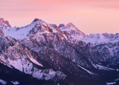 the mountains are covered in snow at sunset