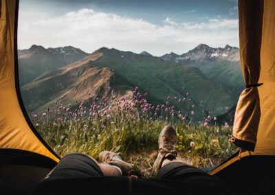 person lying inside tent and overlooking mountain